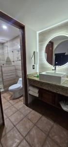 W łazience znajduje się umywalka, toaleta i lustro. w obiekcie Hacienda Suites Loreto w mieście Loreto