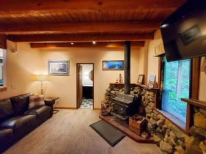 a living room with a couch and a stone fireplace at Juneau Cabin near Eaglecrest & Trails in Juneau