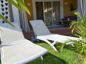 Deux chaises blanches assises dans l'herbe devant une maison dans l'établissement Esmeralda67 Tamarindo, à Bayahibe