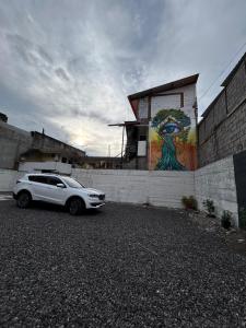 biały samochód zaparkowany przed budynkiem z malowidłem w obiekcie Hospedaje Vacacional y Familiar Baños w Baños