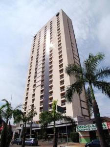 a tall building with palm trees in front of it at Flat confortável e econômico hotel condomínio cristal place in Goiânia