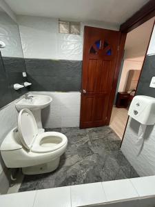 a bathroom with a toilet and a sink at Hospedaje Vacacional y Familiar Baños in Baños