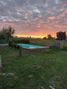 a swimming pool in a field with a sunset at La casita de Isa in Gualeguay