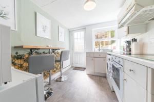 uma cozinha com armários brancos e uma bancada em Charming cottage, Lake District em Little Broughton
