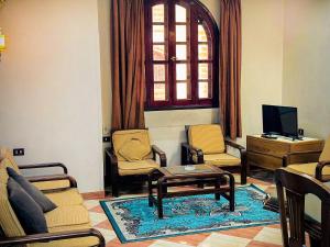ein Wohnzimmer mit Stühlen, einem Tisch und einem TV in der Unterkunft Ramses Downtown Apartment in Luxor