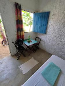 a table and chairs in a room with a window at Hostel Flor da Vida in Canoa Quebrada