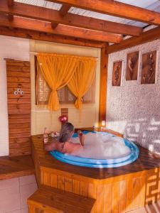 a woman in a bath tub in a room at Magic house banheira de hidromassagem e piscina in Rio Grande