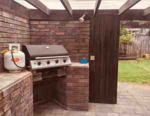 een barbecue in een bakstenen muur in een achtertuin bij Mollies Place - Waihi Beach Holiday Unit in Waihi Beach