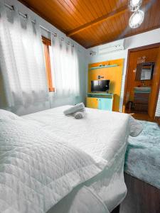 a bedroom with a white bed and a kitchen at Magic house banheira de hidromassagem e piscina in Rio Grande