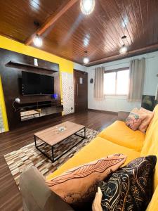a living room with a yellow couch and a table at Magic house banheira de hidromassagem e piscina in Rio Grande