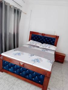 NANCY في يمبي: سرير مع اللوح الأمامي الأزرق في الغرفة