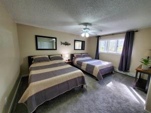 a bedroom with two beds and a ceiling fan at Ocean & Mountain View Duplex, both sides in Juneau