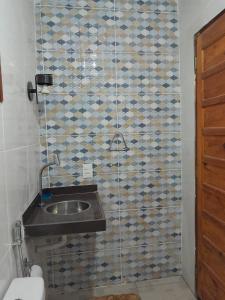 a bathroom with a sink and a tiled wall at Chalé Primavera in Guaramiranga