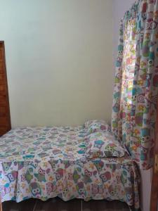 a bed with a comforter on it in a bedroom at Chalé Primavera in Guaramiranga