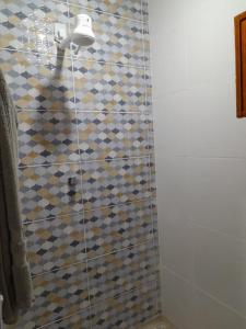 a bathroom with a shower with a tiled wall at Chalé Primavera in Guaramiranga