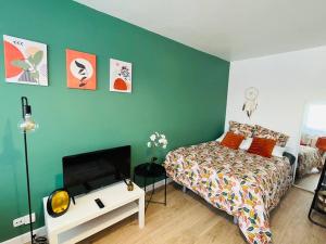 1 dormitorio con cama y pared azul en Grand studio avec Parking 10 min U-Arena La Défense, en Houilles