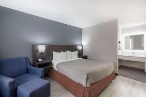 ein Hotelzimmer mit einem Bett und einem blauen Stuhl in der Unterkunft Quality Inn Memphis Downtown in Memphis