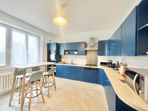 een keuken met blauwe kasten en een tafel en stoelen bij MAISON LAGRANGE - 3 chambres Quartier IUT Hôpital in Quimper