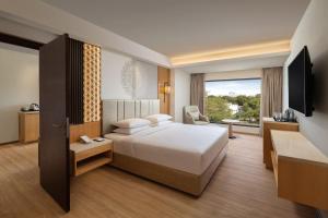 a hotel room with a bed and a television at Courtyard by Marriott Tiruchirappalli in Tiruchchirāppalli