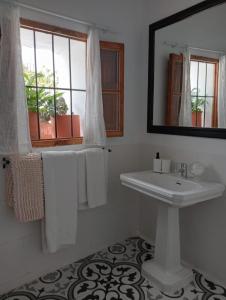 baño blanco con lavabo y ventana en Jardin de Mucho, en Macharaviaya