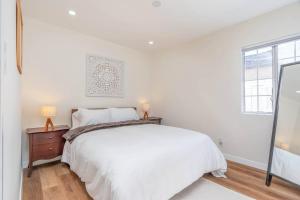 a white bedroom with a bed and a window at Acogedora Casa Cerca de Todo in Los Angeles