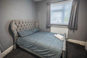 Alaya’s home في Great Burstead: غرفة نوم صغيرة مع سرير مع لحاف أزرق ونافذة