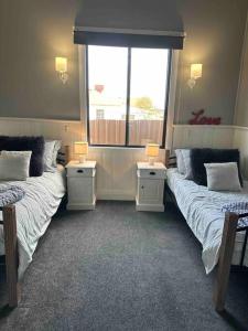 Una habitación con dos camas y dos mesas con lámparas. en Charming 3 bedroom wine country cottage, en Rutherglen