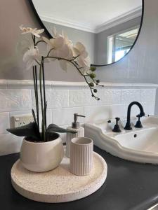 Un baño con un lavabo y un jarrón con flores blancas. en Charming 3 bedroom wine country cottage, en Rutherglen