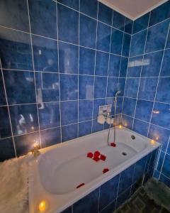 a blue tiled bathroom with a bath tub with roses on it at Apartman Tajna in Sremčica