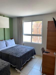 1 dormitorio con cama y ventana grande en Flat Beira mar de João Pessoa no Bairro Cabo Branco, en João Pessoa