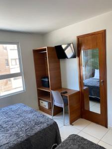1 dormitorio con cama y escritorio con espejo en Flat Beira mar de João Pessoa no Bairro Cabo Branco, en João Pessoa