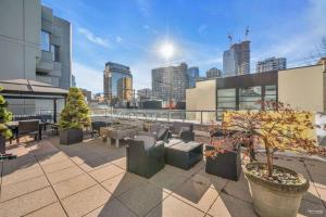 a rooftop patio with furniture and a view of a city at Modern Condo in the Heart of DT Overlooking City in Vancouver