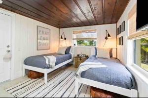 two beds in a bedroom with white walls and wooden ceilings at Coastal Oasis Of Lantana in Lantana