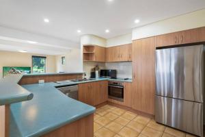 a kitchen with wooden cabinets and a stainless steel refrigerator at Reef in Lennox Head