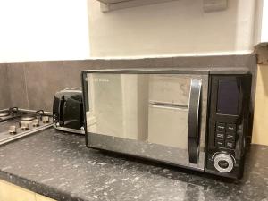 a microwave oven sitting on a counter in a kitchen at Hometel Nice Comfy Apartment Can Sleep 9 in Leicester