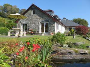 a stone house with an umbrella and a pond at Heulwen Guest House in Dolgellau