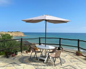 a table and chairs with an umbrella and the ocean at Ekilibrium in Los Órganos