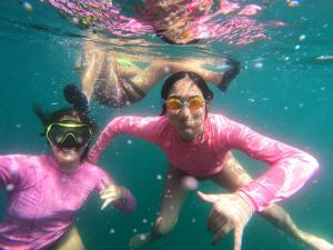 two people in pink shirts swimming in the water at Ekilibrium in Los Órganos