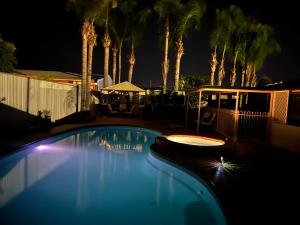 a swimming pool at night with palm trees at Shazza’s Desert Oasis in Broken Hill