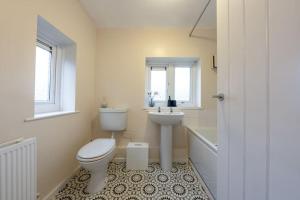a bathroom with a toilet and a sink and a tub at Modern Wolverhampton 3 bed Home in Wolverhampton +21 photos