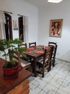 een eetkamer met een tafel en stoelen en een plant bij Pousada da Sissi in Itanhaém