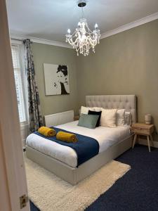 a bedroom with a bed with yellow pillows and a chandelier at Stylish apartment in Walmer (nr Deal&Dover) in Walmer