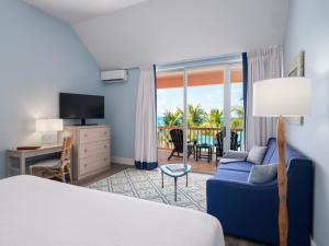 a hotel room with a bed and a couch and a balcony at The Reefs Resort and Club in Southampton