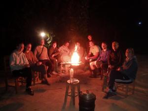 um grupo de pessoas sentadas à volta de uma fogueira à noite em NongKhiaw CampingSite Swimming Pool em Ban Nongkham