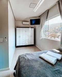 um quarto com uma cama, uma televisão e uma janela em Morada da Lagoinha em Florianópolis