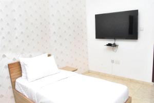 Ibadan Serviced Apartments في إيبادان: غرفة نوم بسرير وتلفزيون بشاشة مسطحة