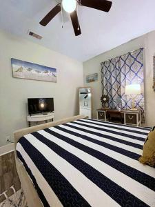 ein Schlafzimmer mit einem schwarz-weißen gestreiften Bett und einem TV in der Unterkunft The Poolside Bungalow in Galveston