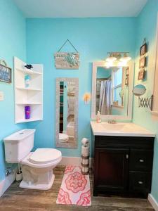 y baño con aseo, lavabo y espejo. en The Poolside Bungalow en Galveston