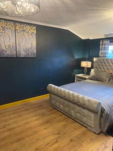 Schlafzimmer mit einem Bett mit blauer Wand in der Unterkunft Alaya's Homes 4 bedroom house in Pitsea