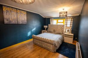 a bedroom with a bed and a blue wall at Alaya's Homes 4 bedroom house in Pitsea